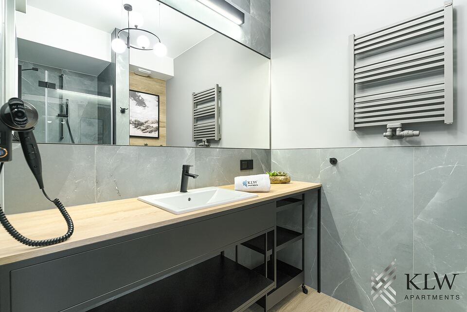 Łazienka: duże lustro nad blatem z umywalką, w odbiciu kabina prysznicowa